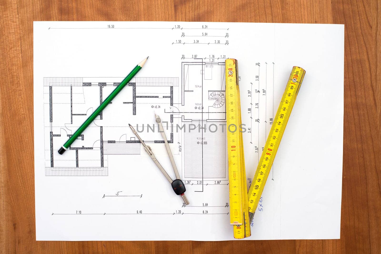 building plan with pencil, folding yardstick and compass on wooden table
