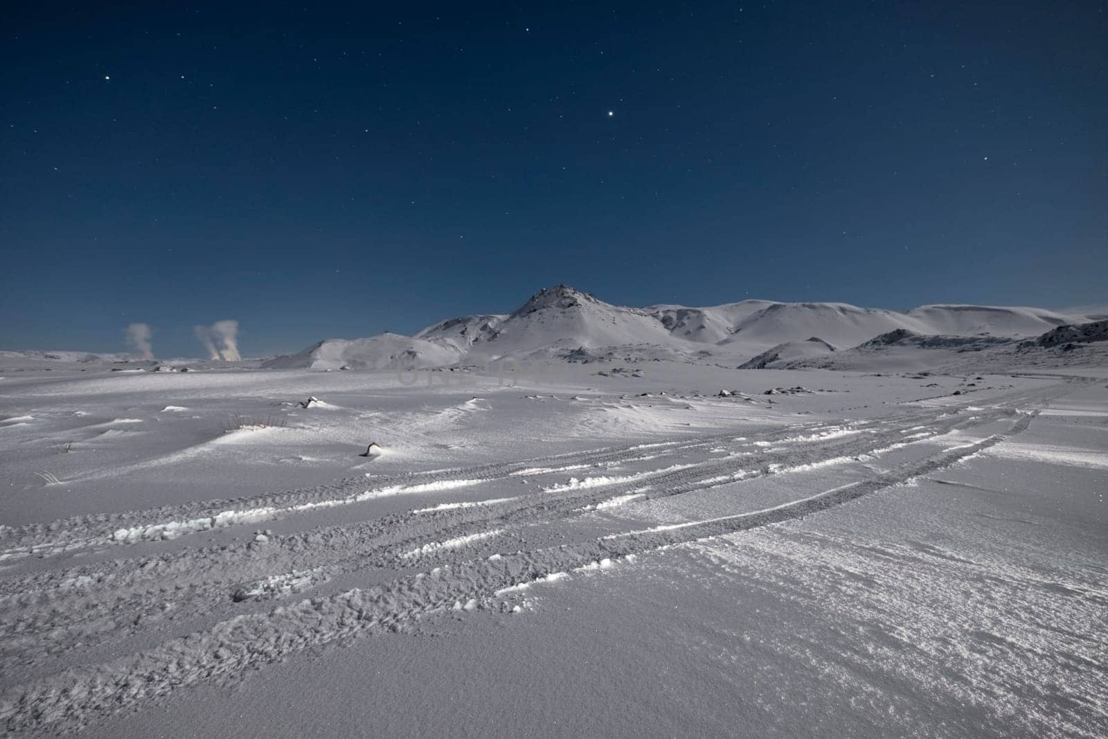 Starry sky over snow covered mountains in the wintertime