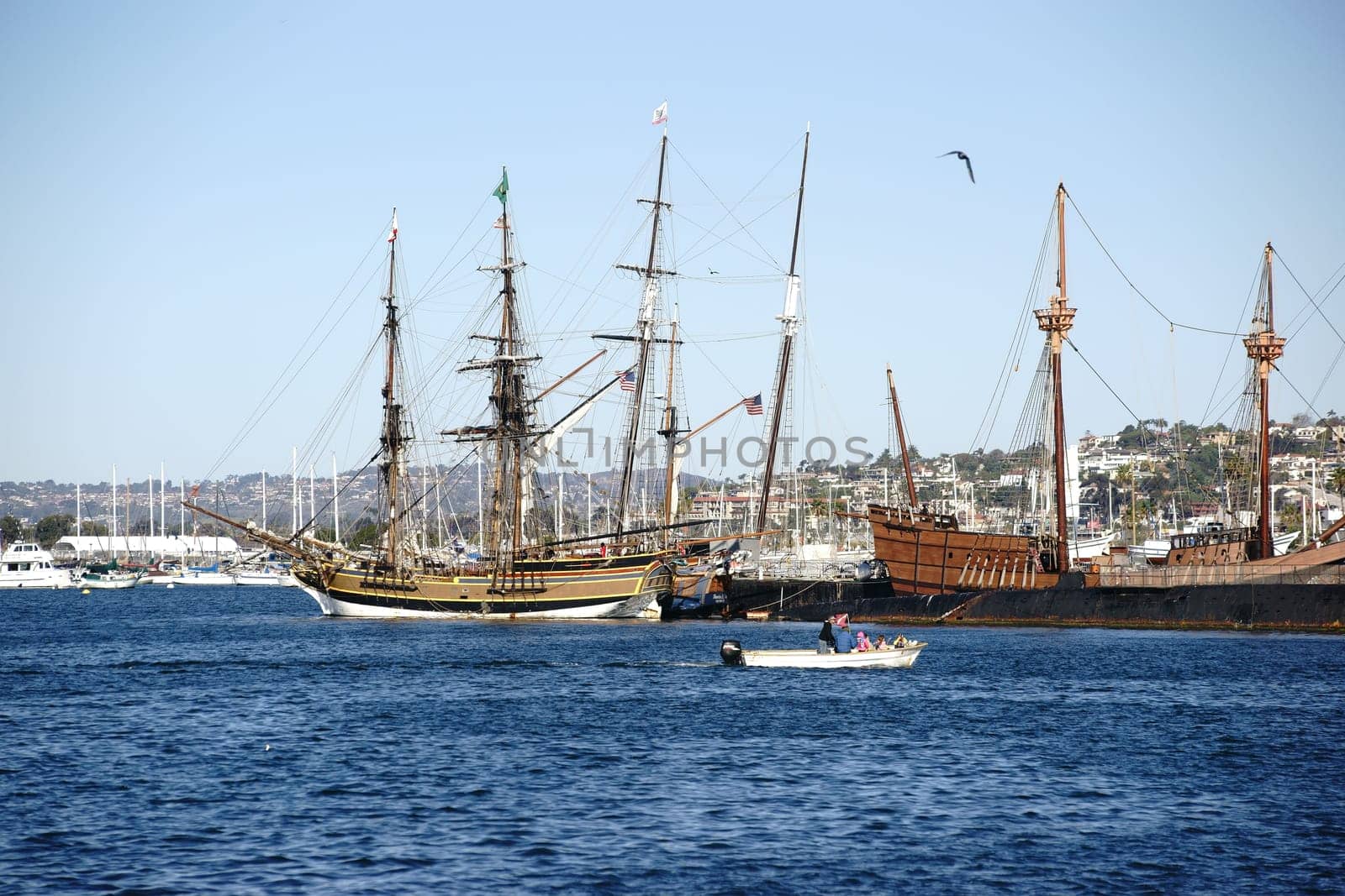San Diego,United States - December 25,2015: A motorboat sails past the ancient and historic sailing ships of the San Diego Maritime Museum at the Port of San Diego on December 25,2015.