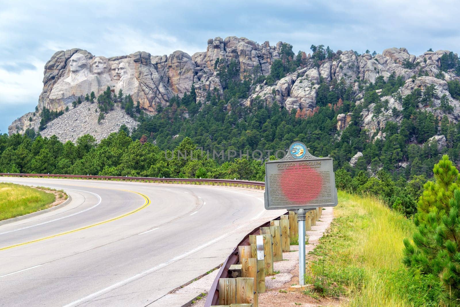 Highway leading to Mount Rushmore with a sign dedicated to Gutzon Borglum in the foreground