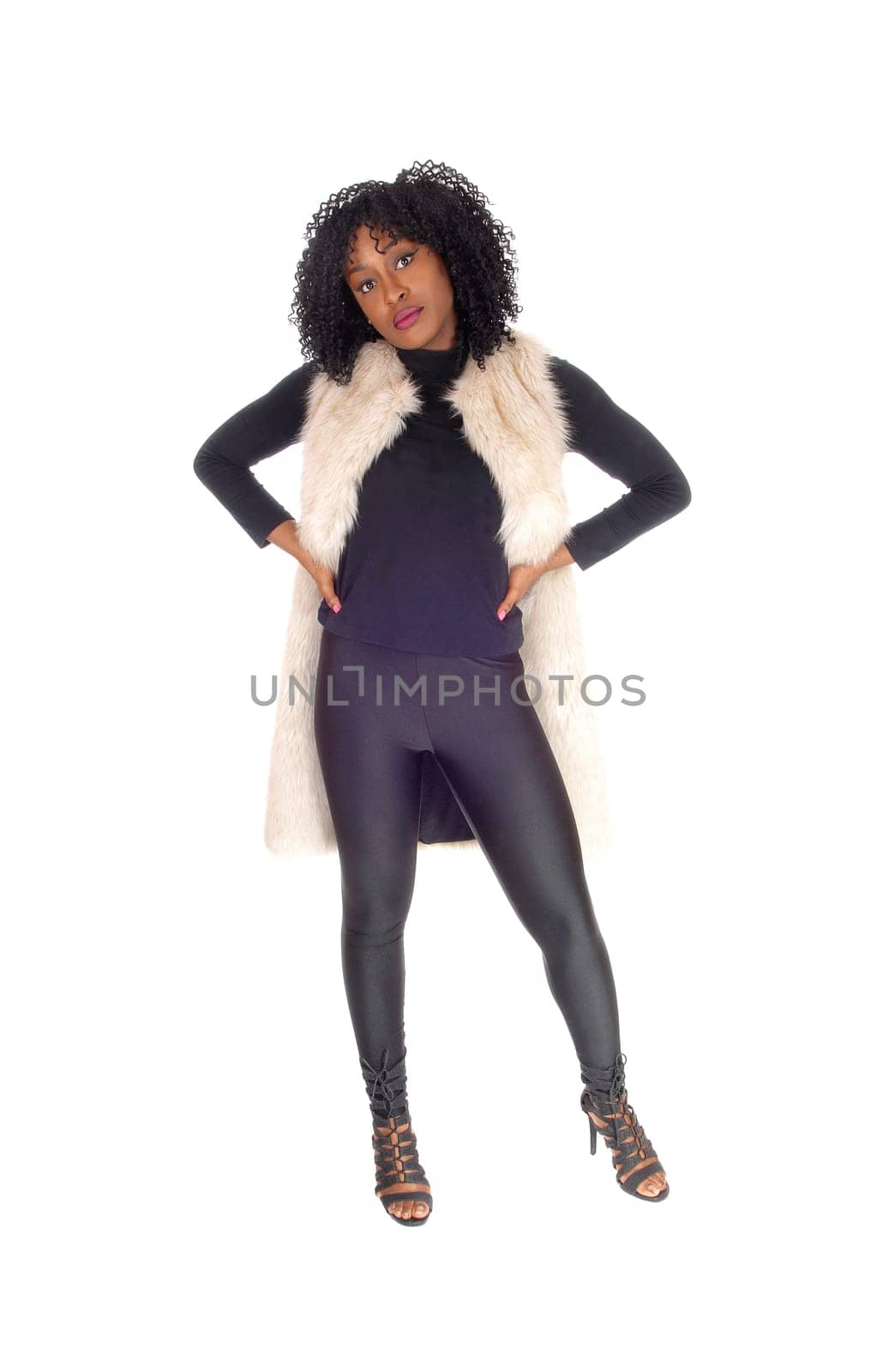 A lovely young African American woman in black tights and a white.fur coat with her hands on her hips, isolated for white background..