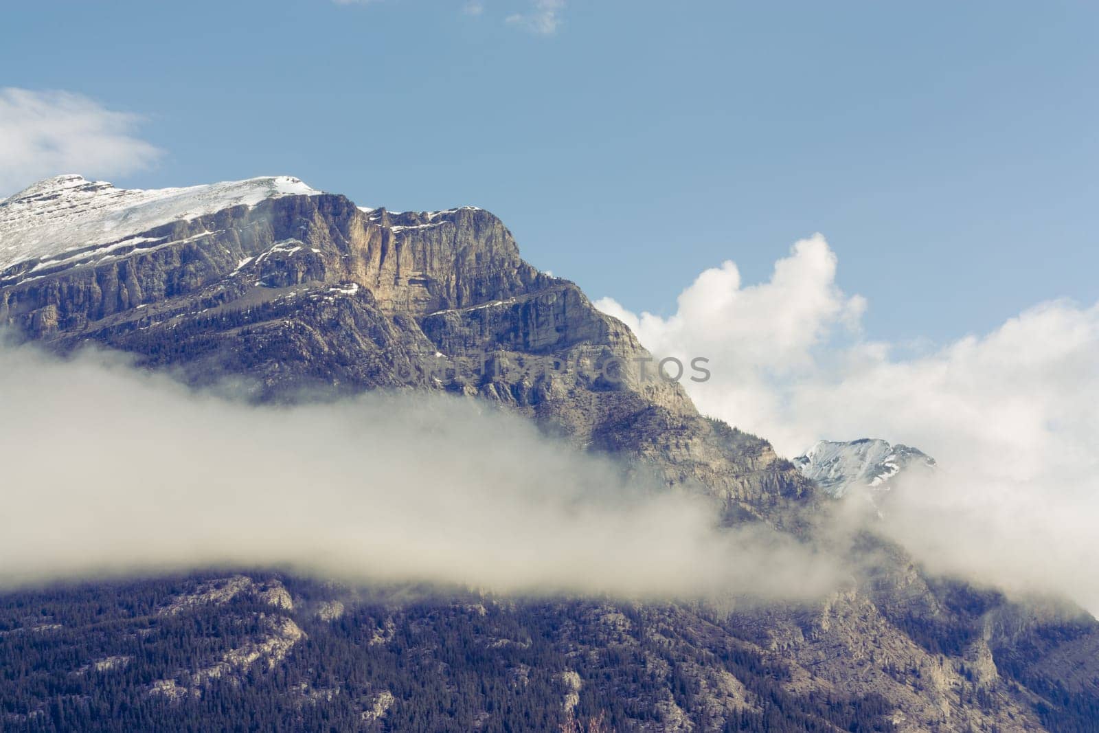Close up of the snow capped peak of Grotto Mountain with a cloud.