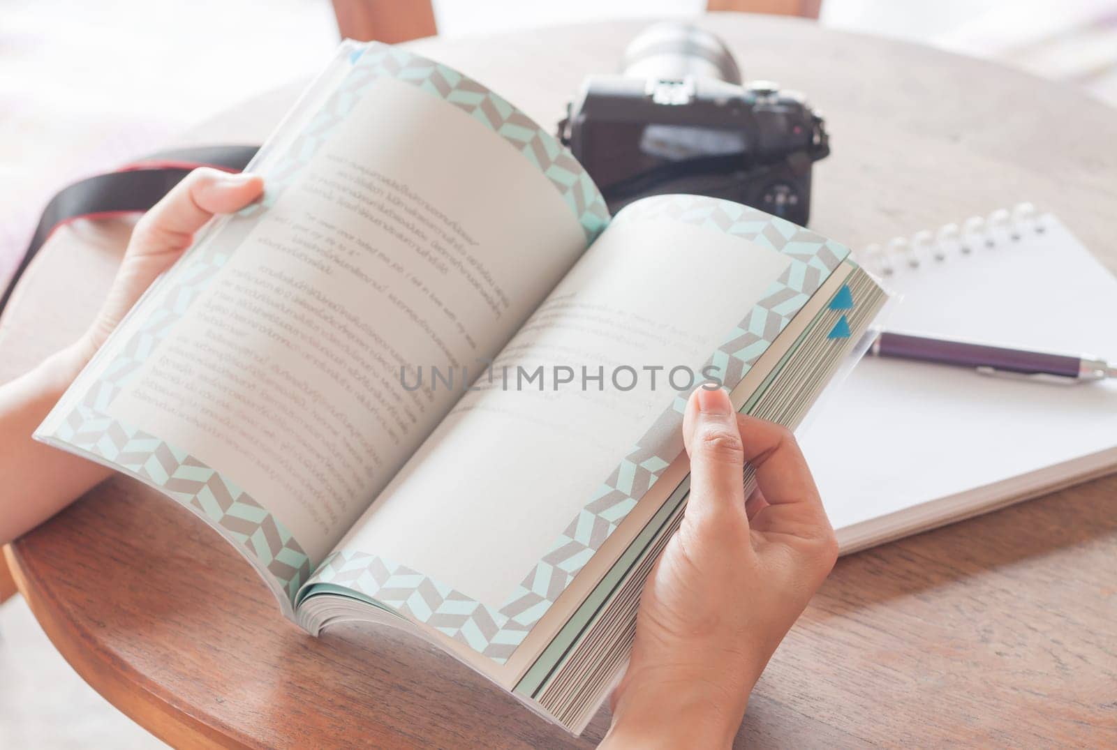 Woman reading book in coffee shop, stock photo
