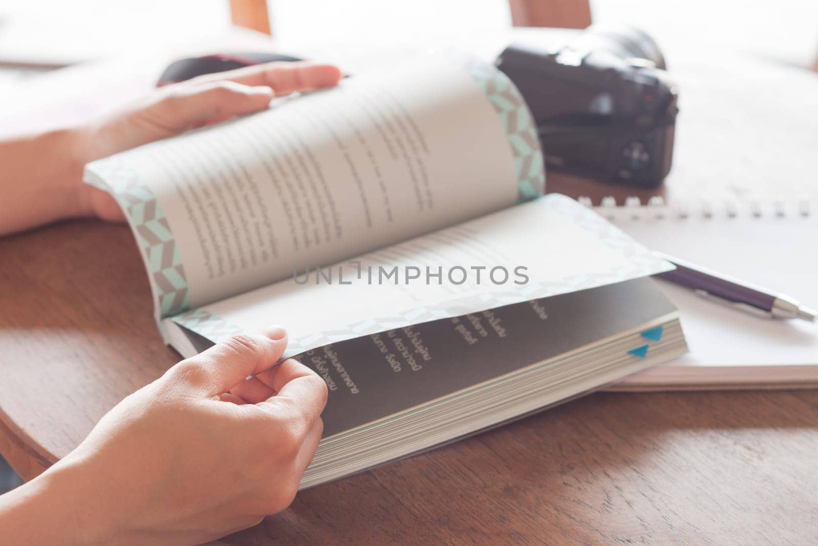 Woman reading book in coffee shop, stock photo