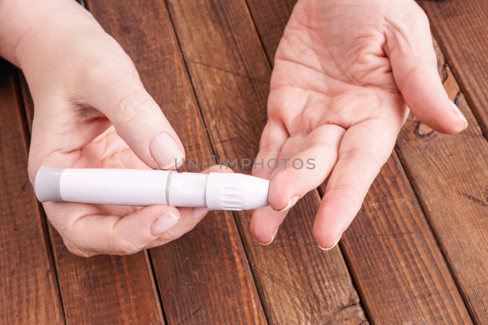 a lady&#39 s hands measuring blood glucose with a home test to control her diabetes