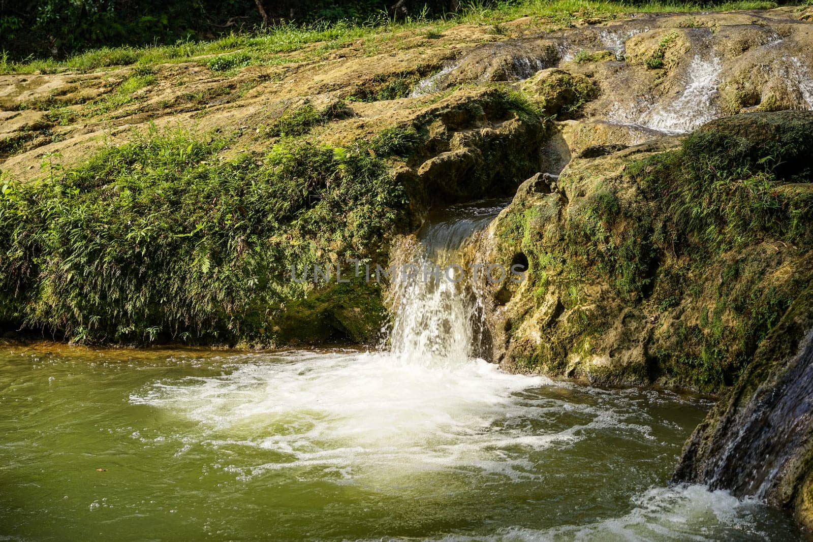 landscape with small waterfall by the lake on a summer day and green moss on the stones