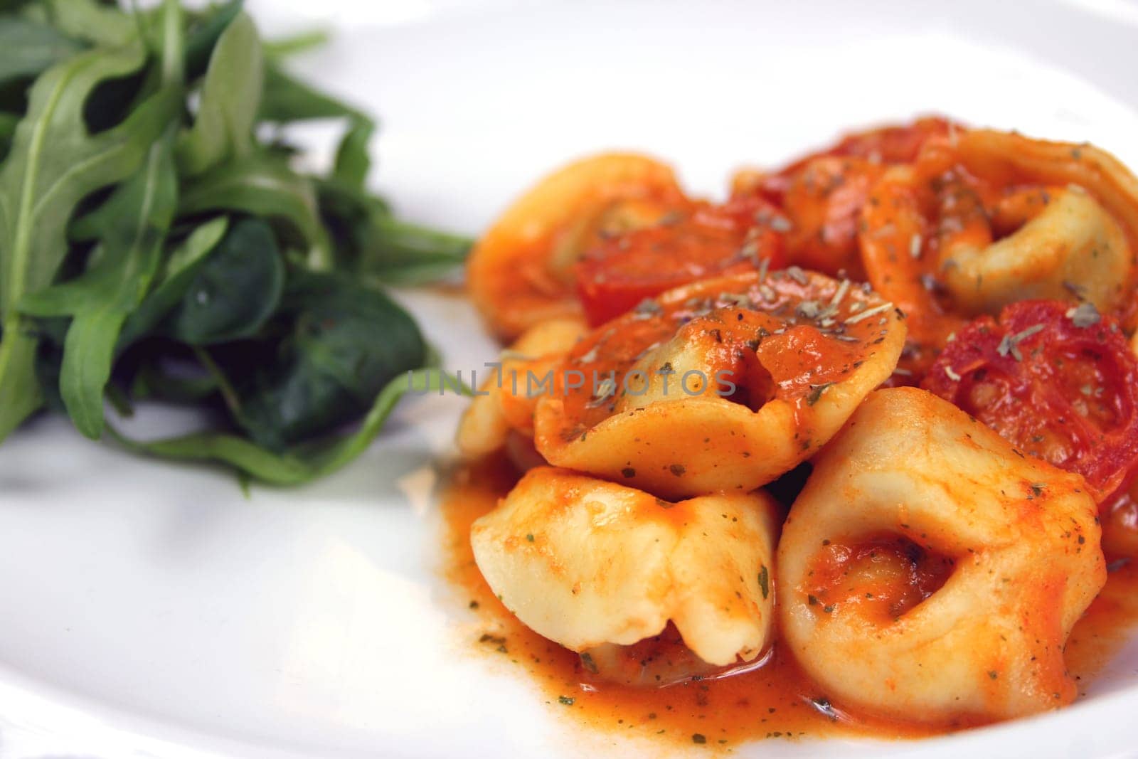tortellini with tomatoes in tomato-cream sauce and garnished with salad