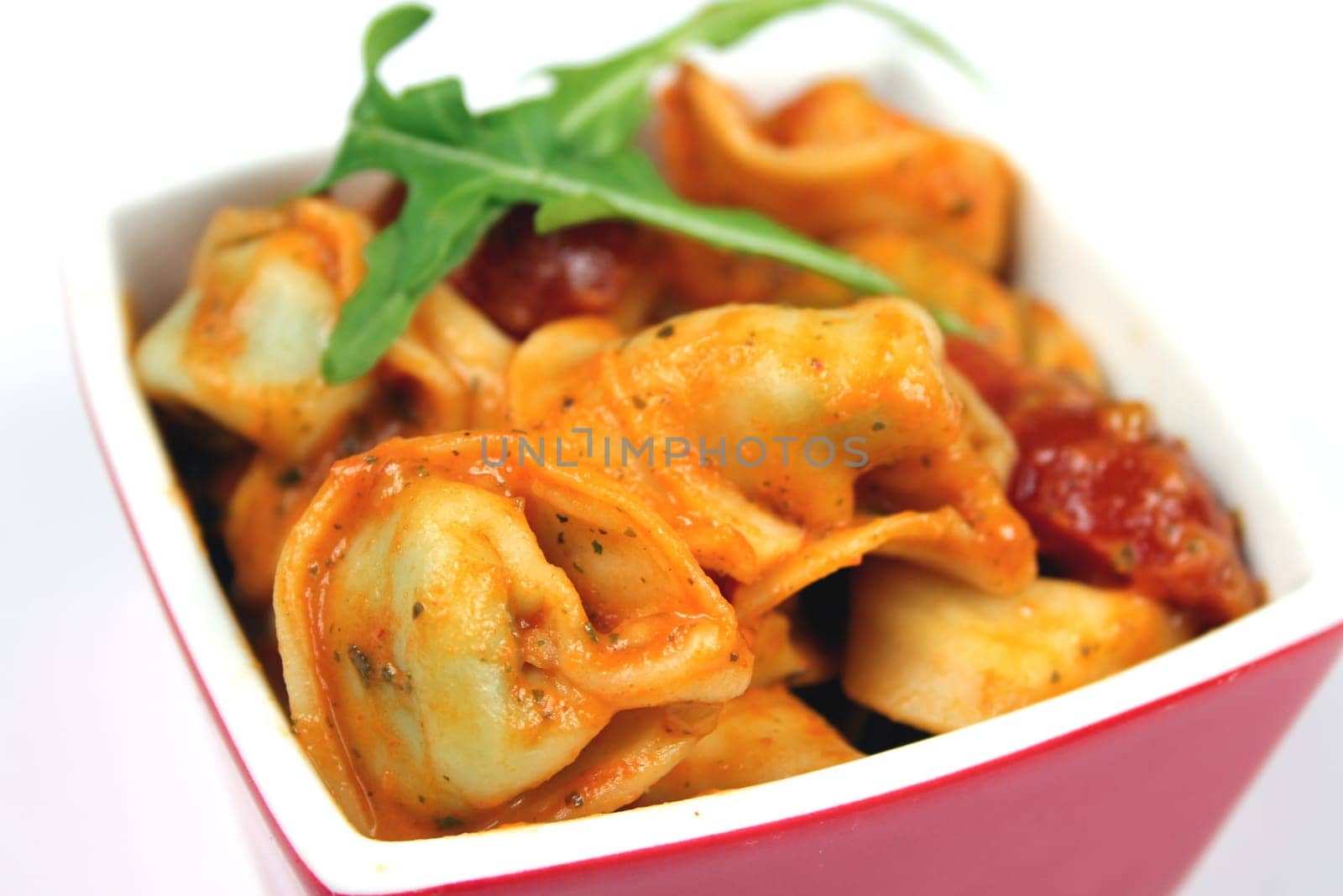 Pasta salad with tortellini and tomatoes,garnished with rocket