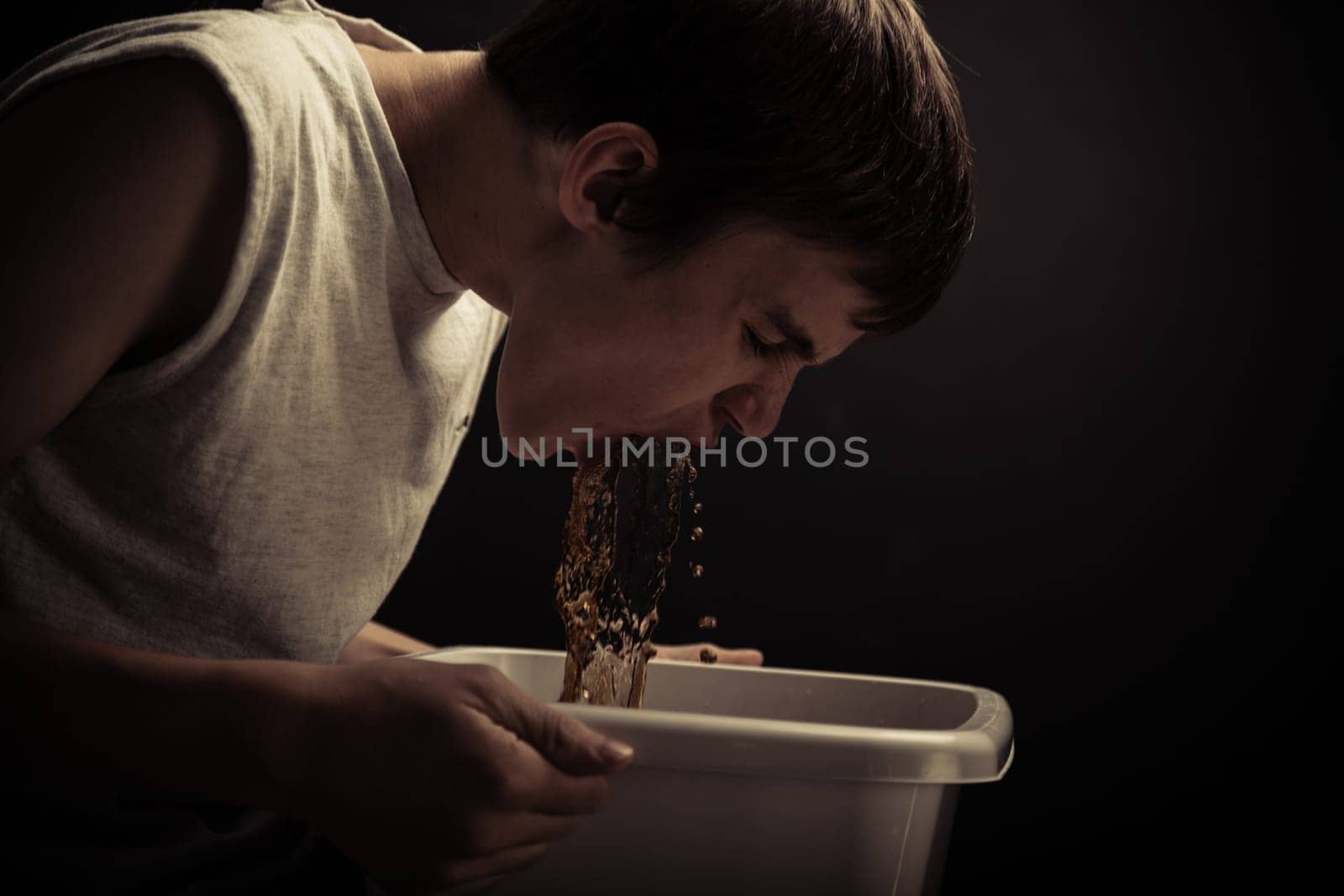 Single male teenager getting sick to his stomach in sink from abusing drugs or alcohol