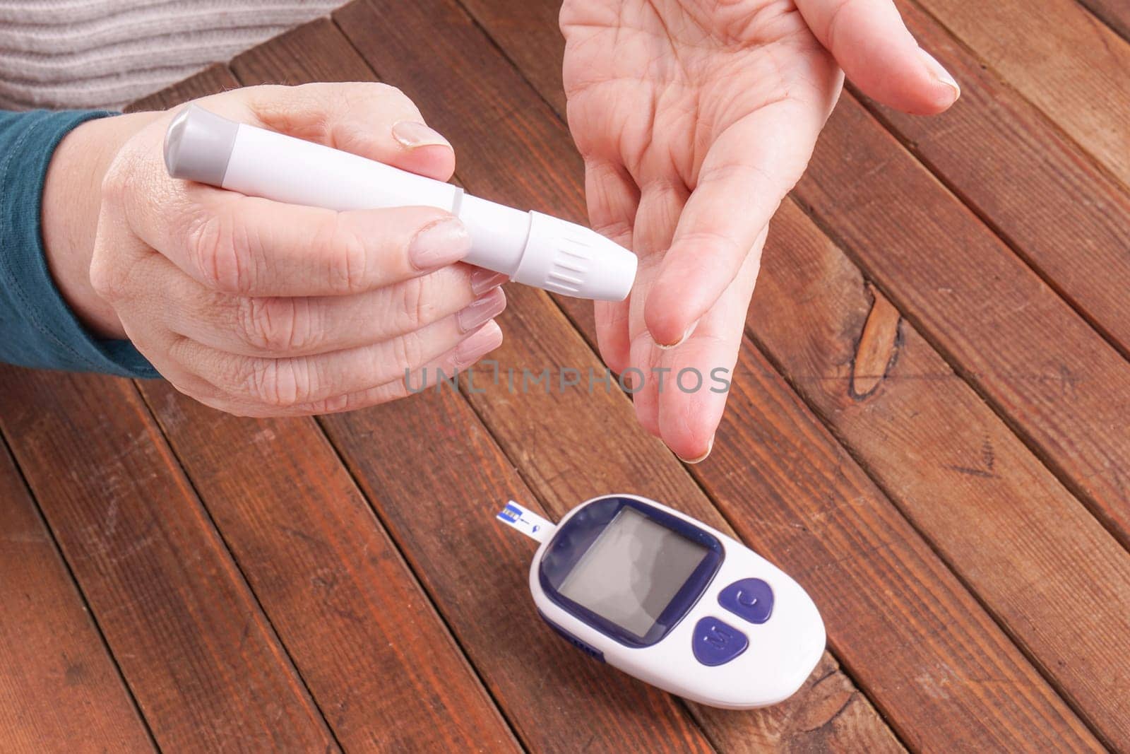 a lady&#39 s hands measuring blood glucose with a home test to control her diabetes