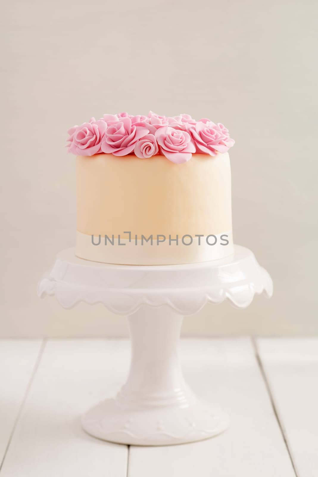 Ivory fondant covered cake with pink sugar roses on cake stand