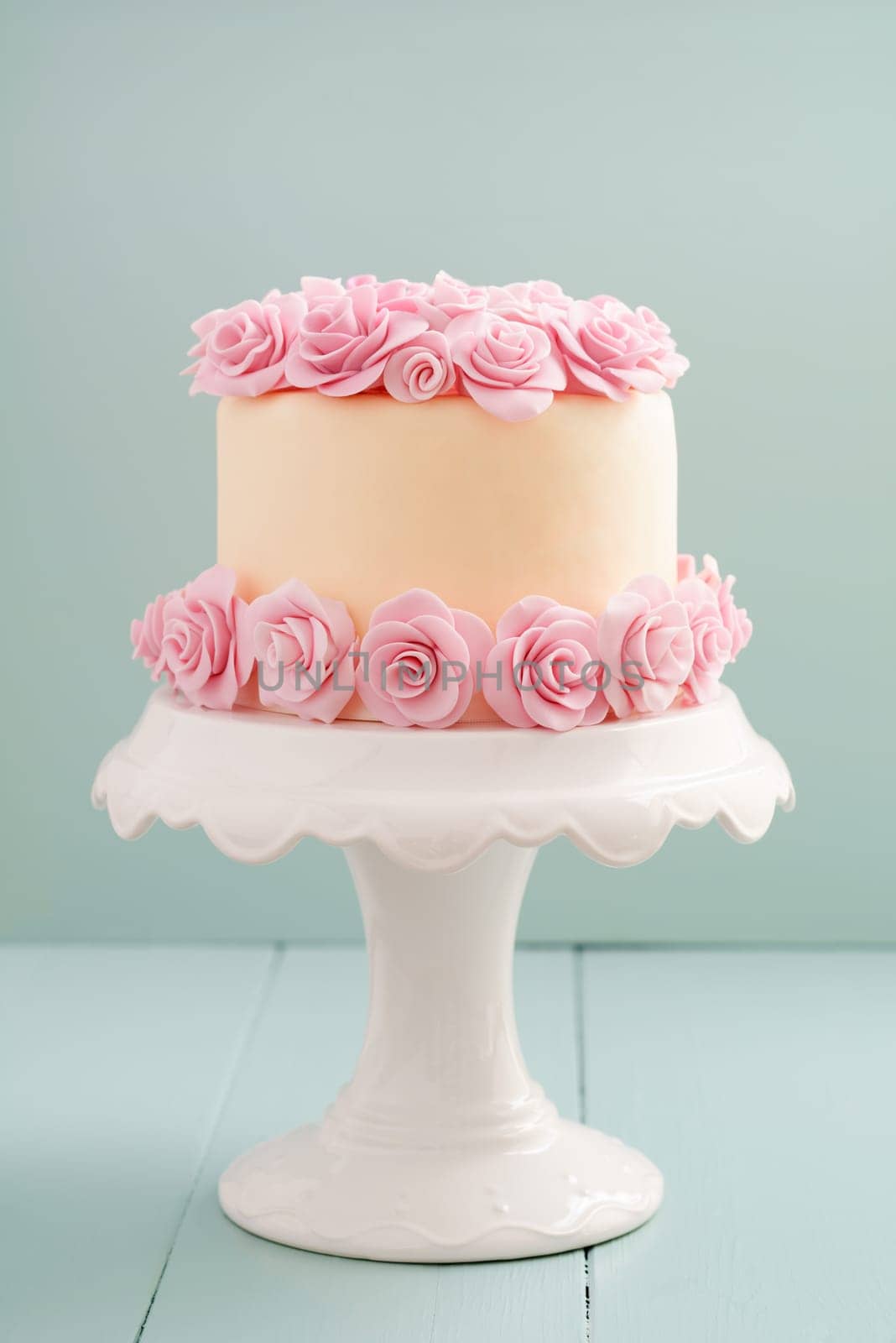 Ivory fondant covered cake with pink sugar roses on cake stand
