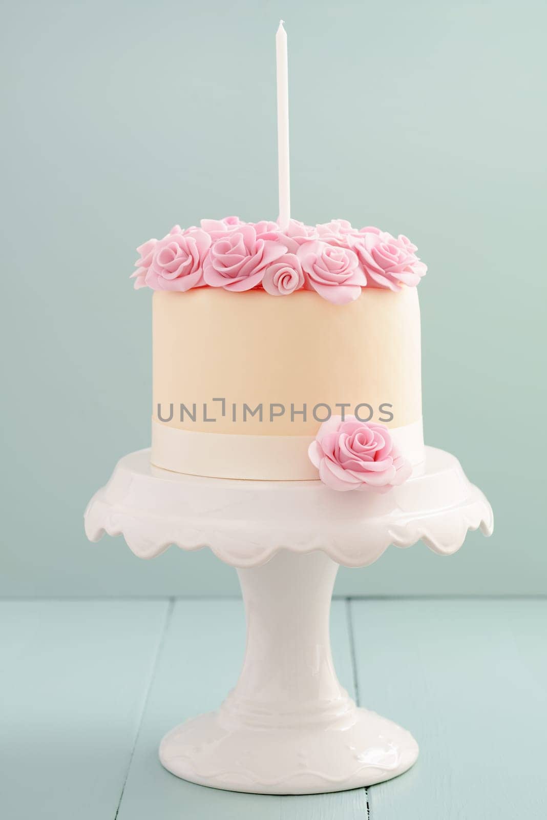 Ivory fondant covered cake with pink sugar roses on cake stand