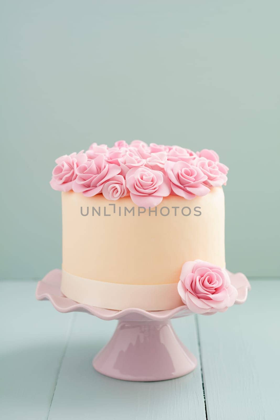 Ivory fondant covered cake with pink sugar roses on cake stand