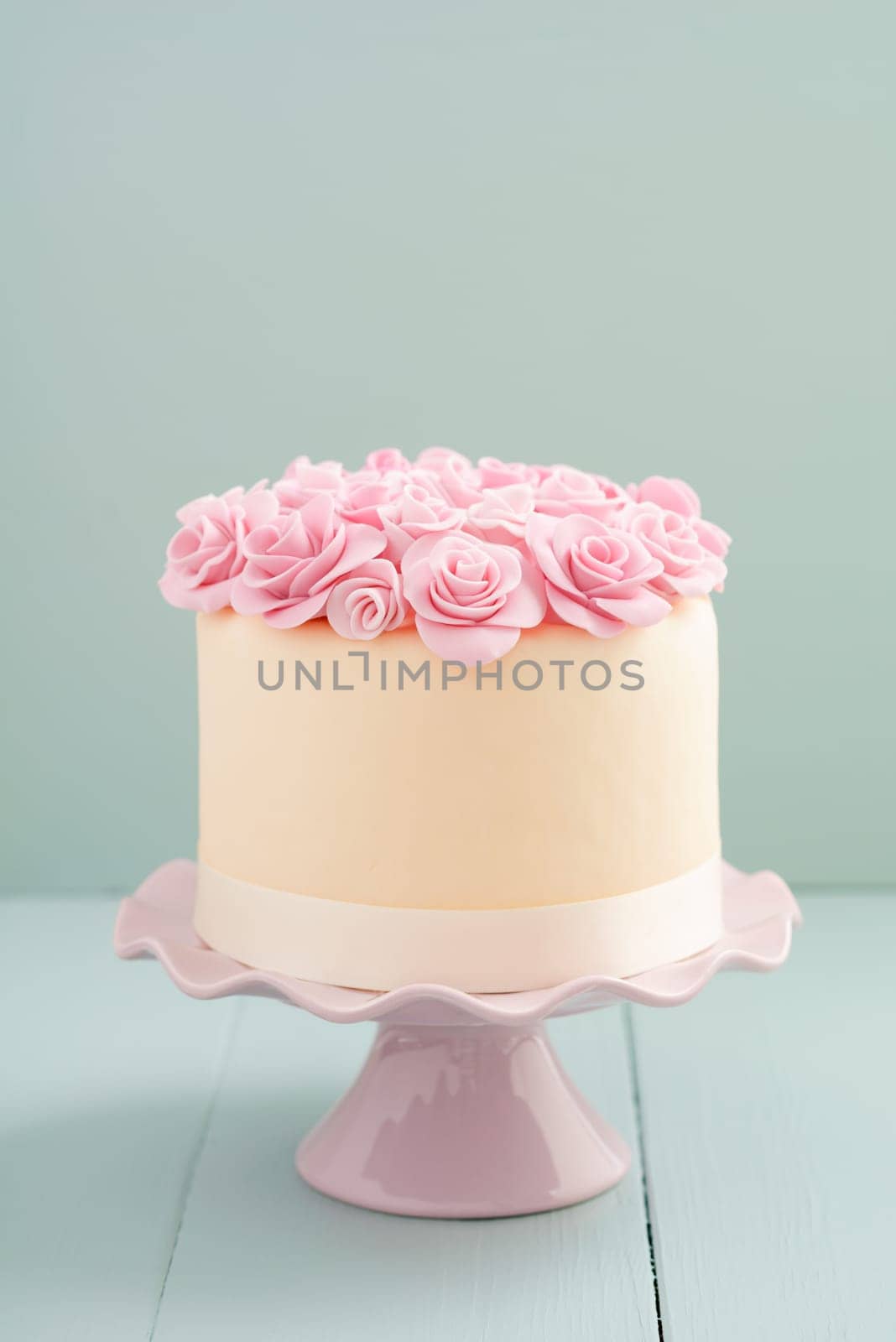 Ivory fondant covered cake with pink sugar roses on cake stand