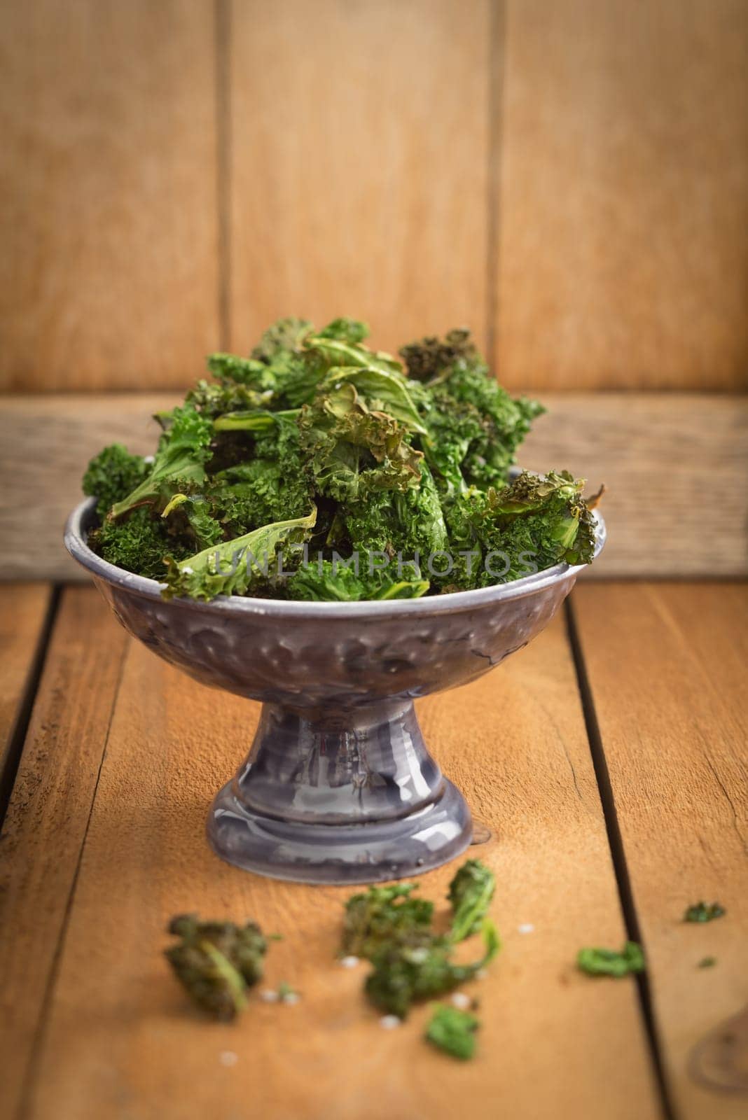 Kale chips with sea salt in a small dark serving bowl