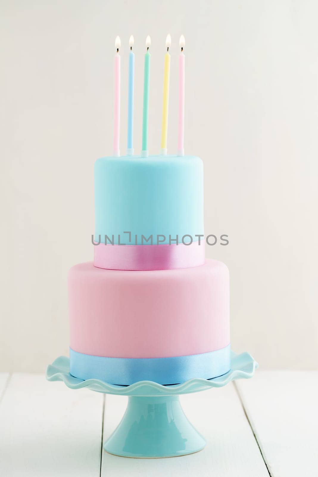 Fondant covered pastels coloured birthday cake with four birthday candles
