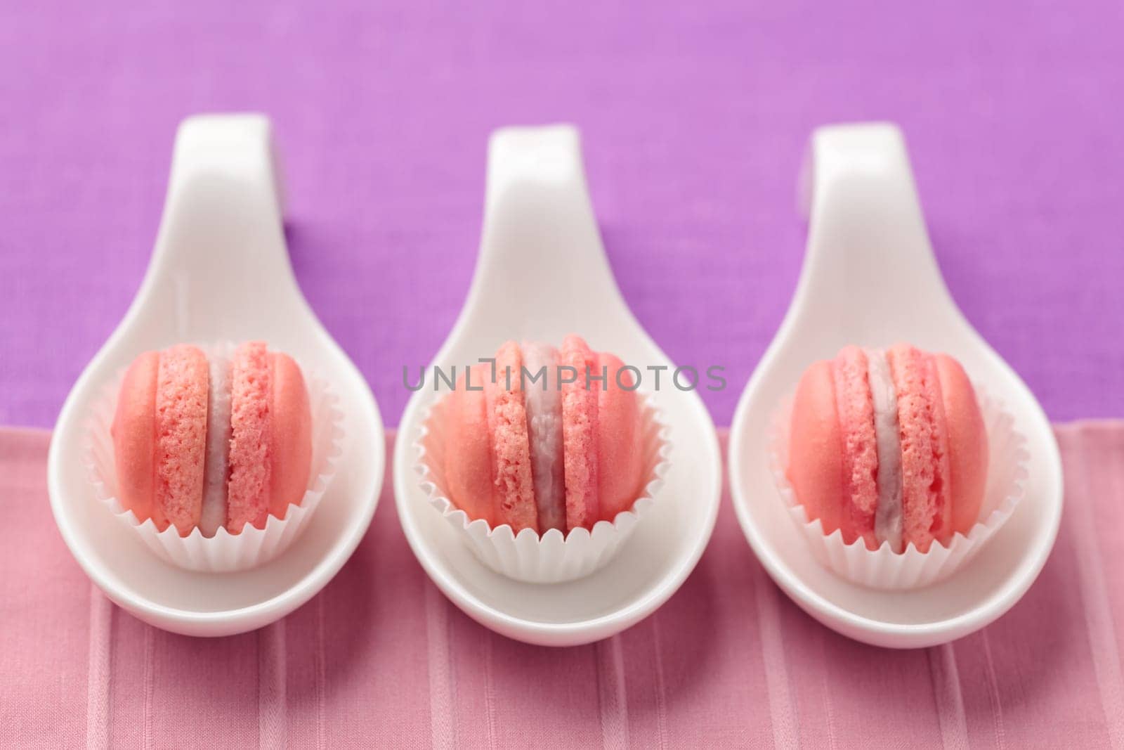Pink macarons with buttercream filling on little spoons