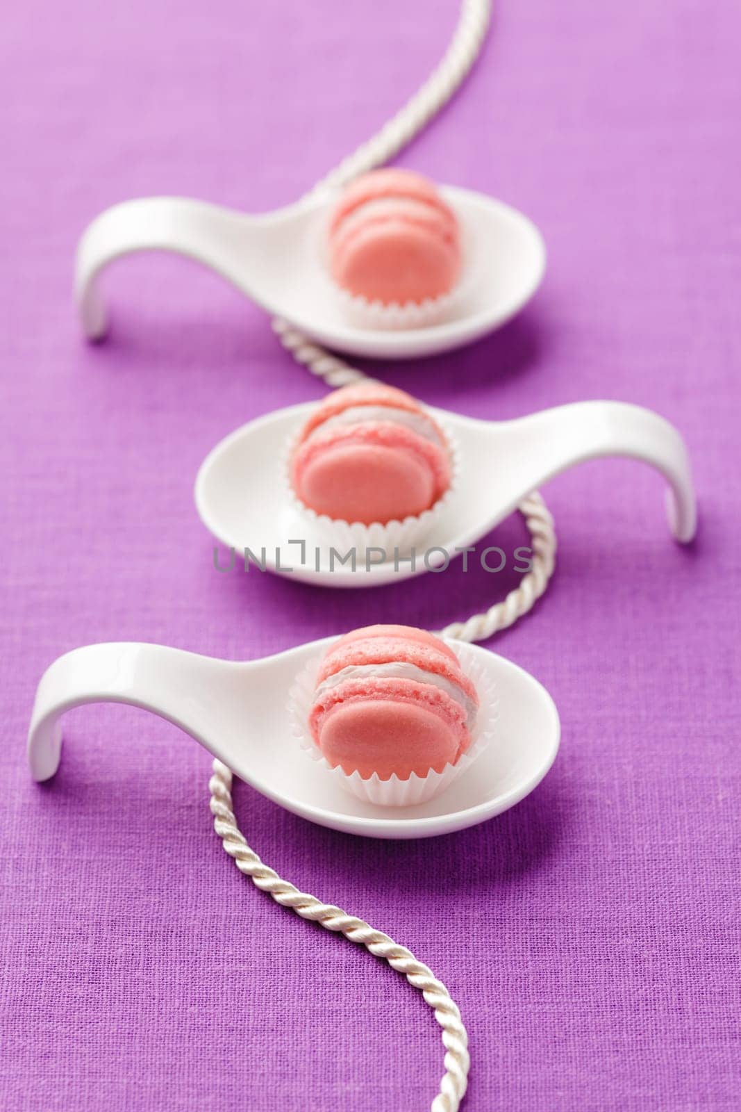Pink macarons with buttercream filling on little spoons