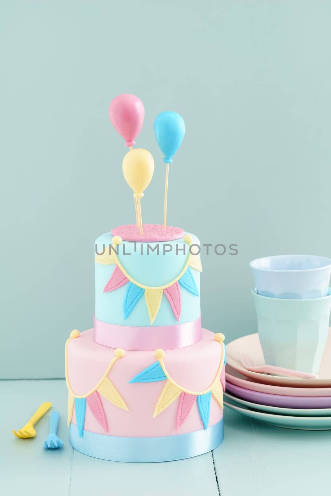 Fondant covered pastels coloured birthday cake with buntings and balloons