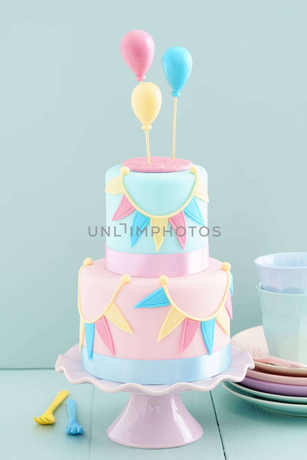 Fondant covered pastels coloured birthday cake with buntings and balloons