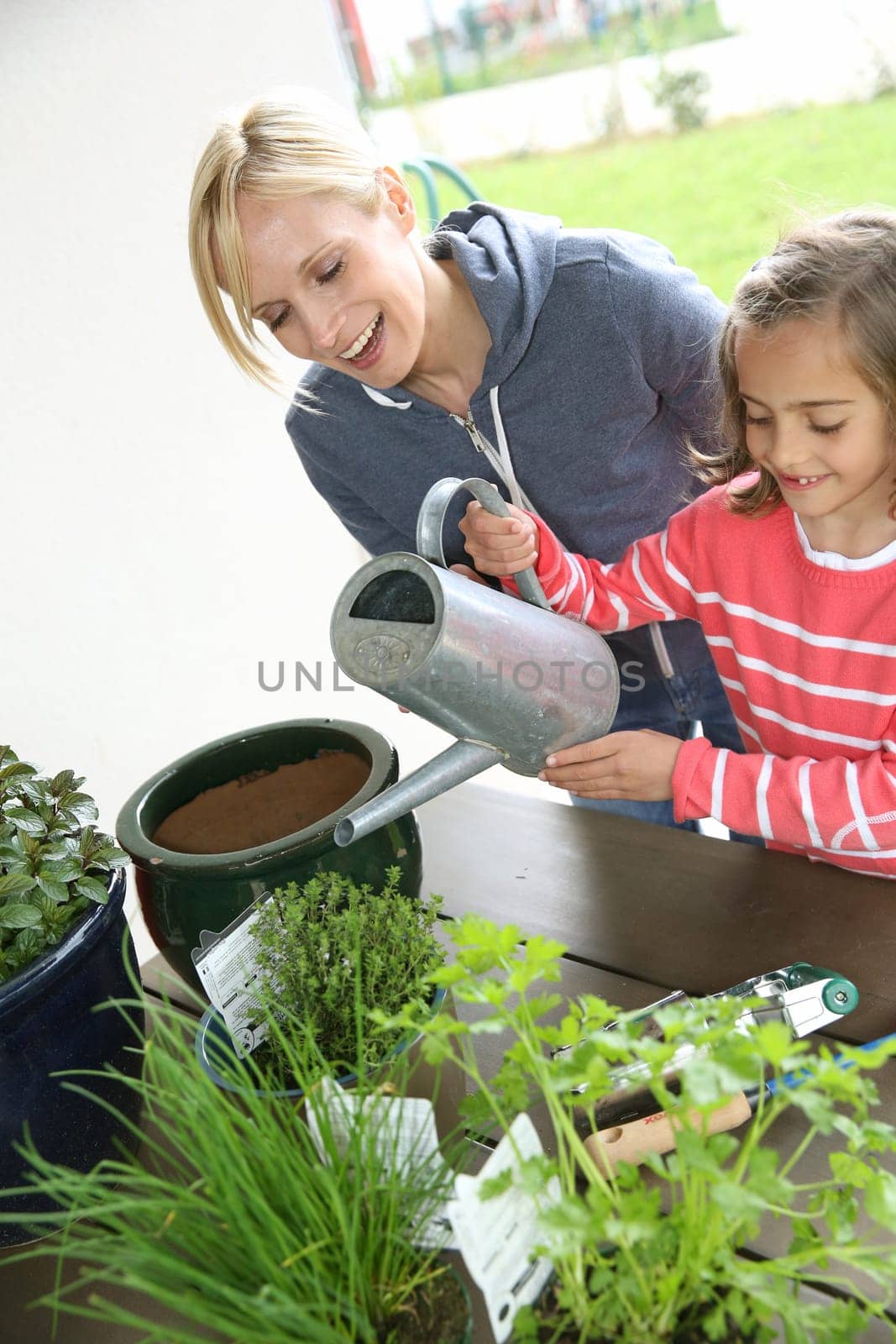 Mother and daughter in garden planting aromatic flowers
