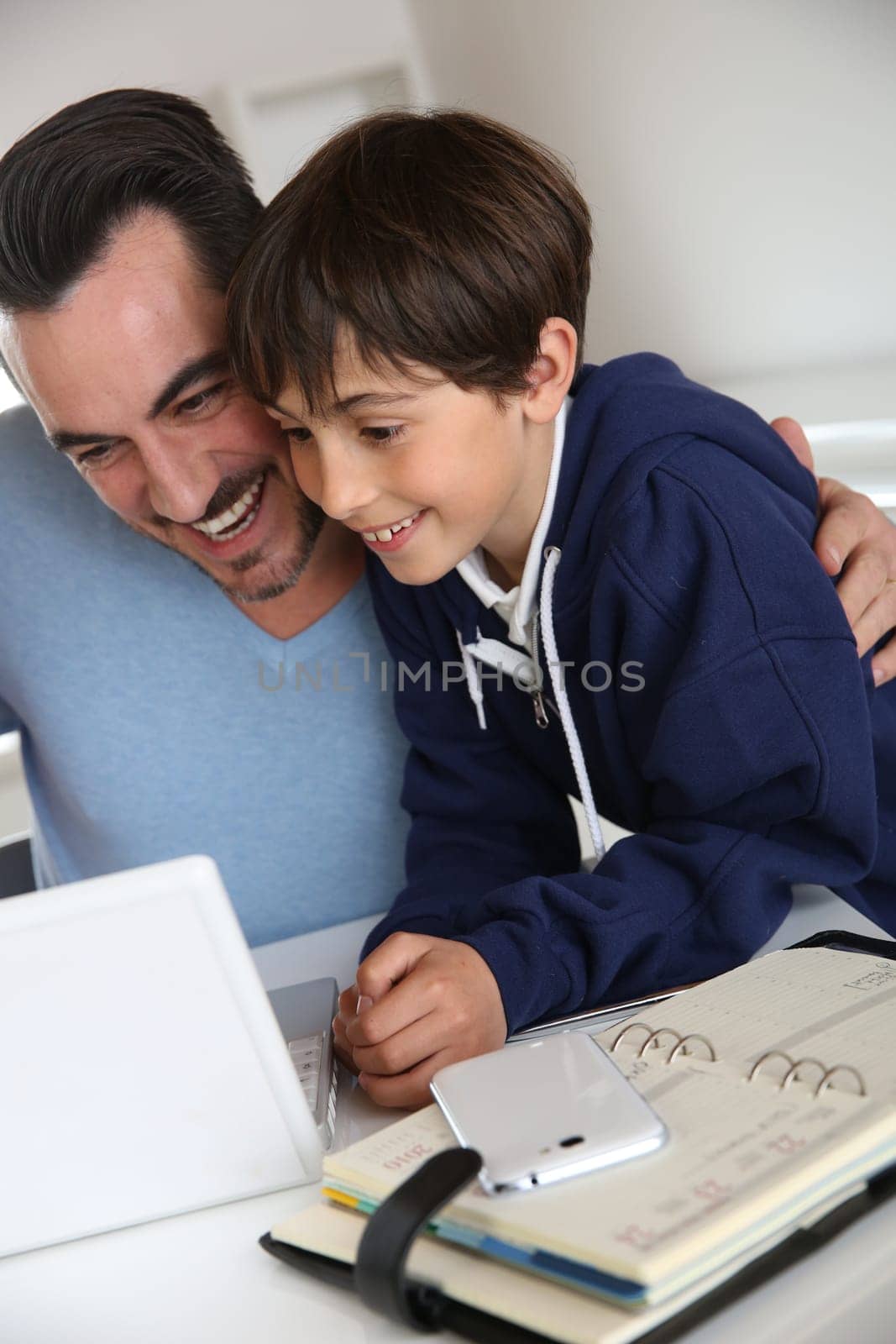 Man showing to young boy how to use laptop