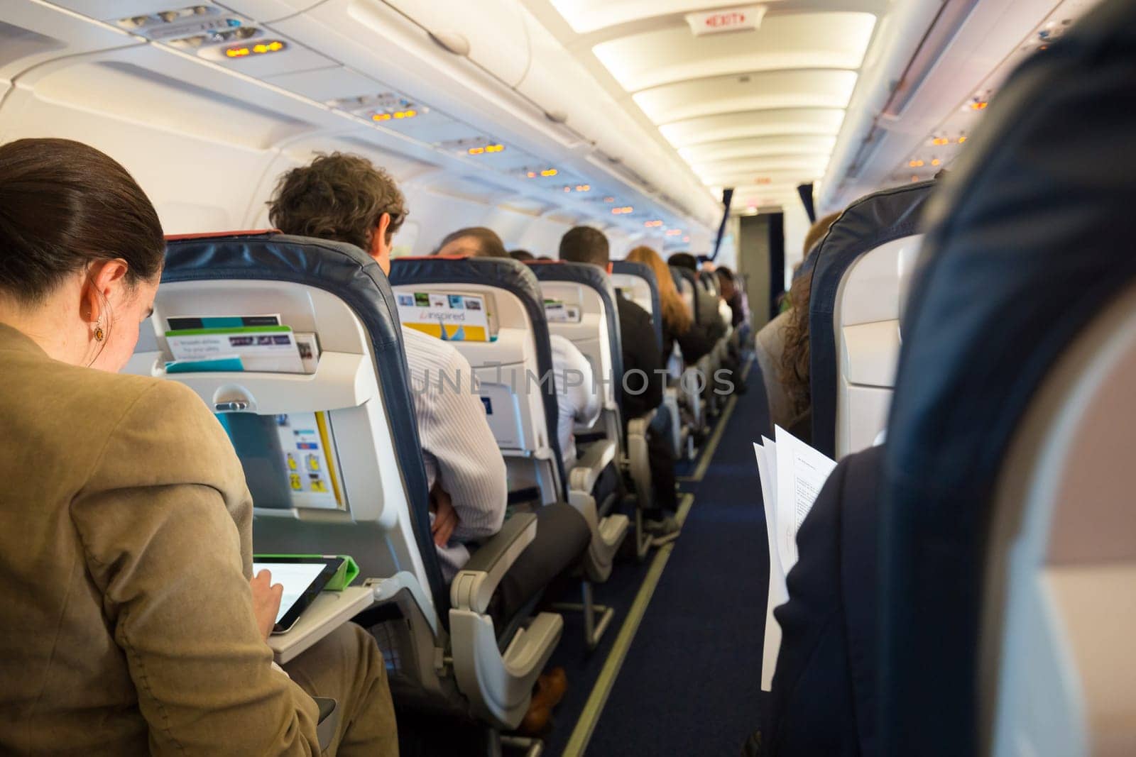Interior of  commercial airplane with passengers on seats waiting to taik off.
