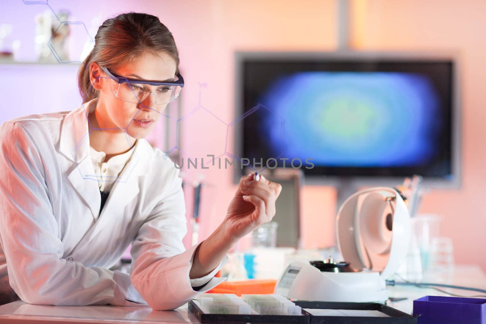 Life science researcher working in laboratory. Portrait of a confident female health care professional in his working environment writing structural chemical formula on a glass board.