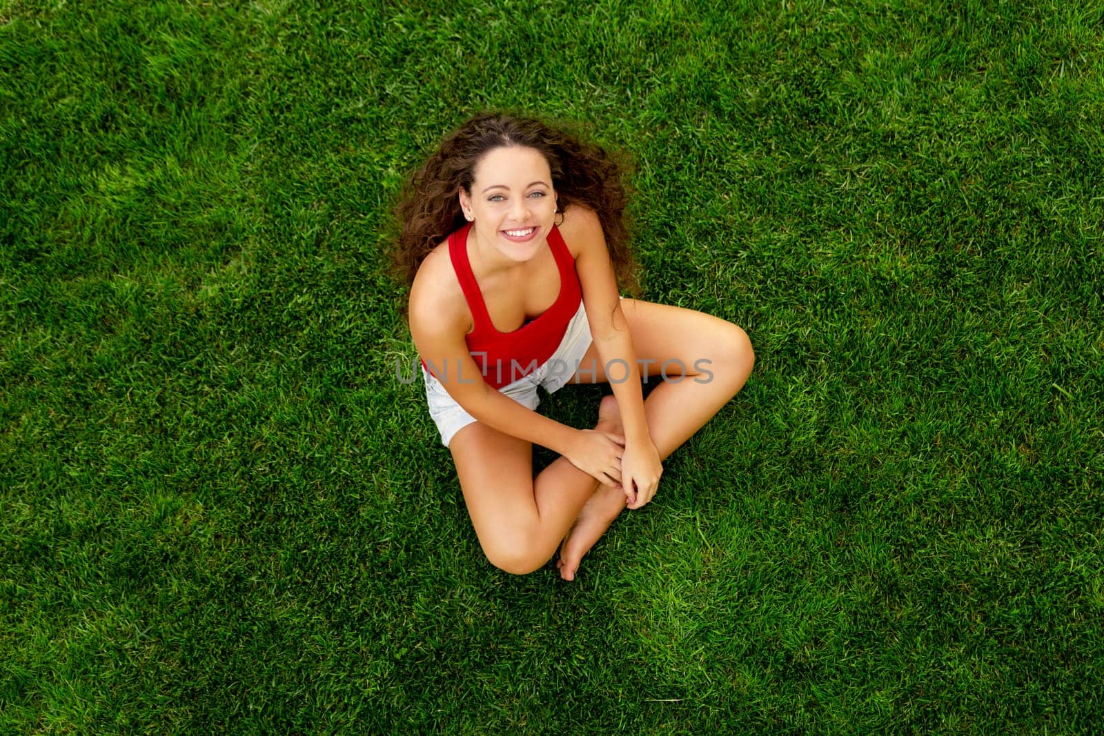 Happy young woman sitting on a blanket with arms stretched
