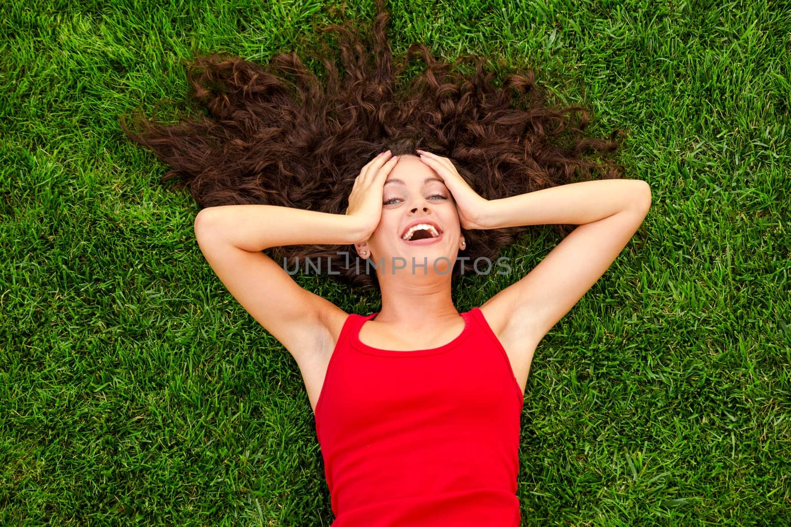 Happy young woman sitting on a blanket with arms stretched