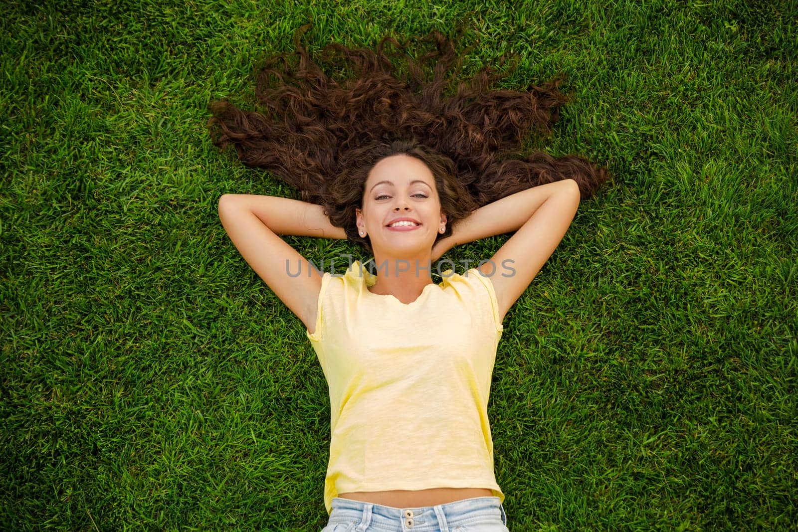 Happy young woman sitting on a blanket with arms stretched