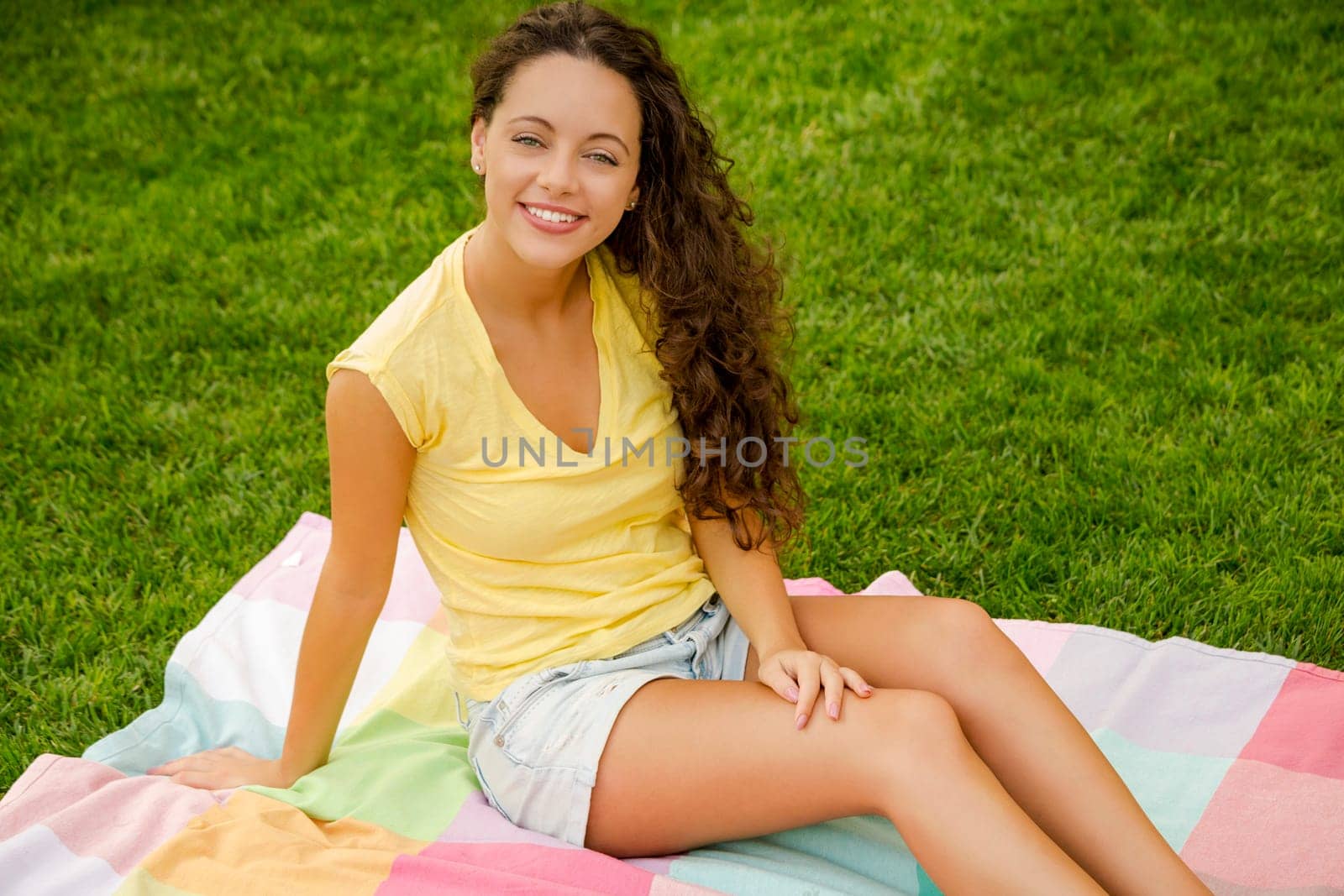 Smiling young woman lying on her back on a blanket and relaxing