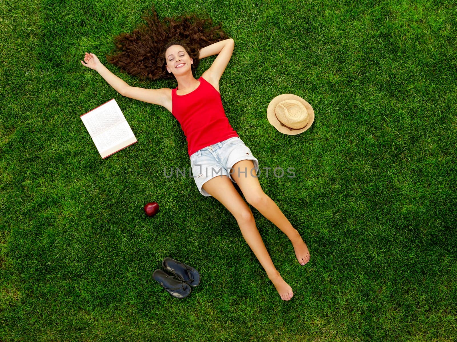Happy young woman sitting on a blanket with arms stretched