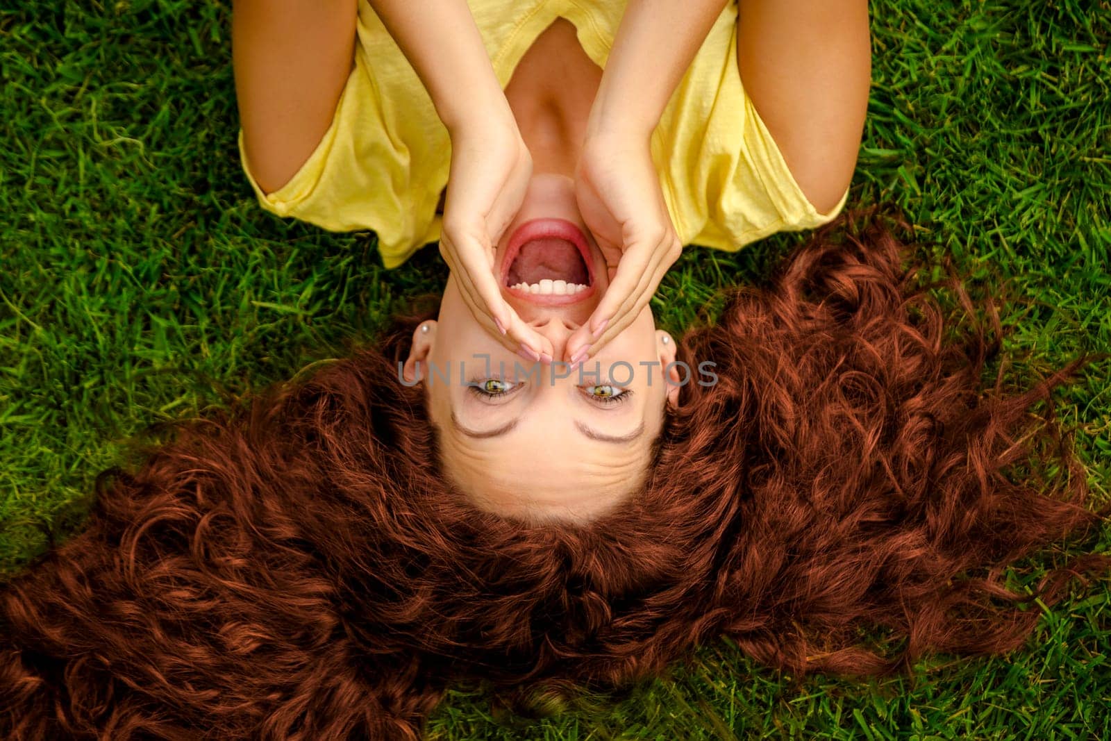 Smiling young woman lying on the grass and making a selfie