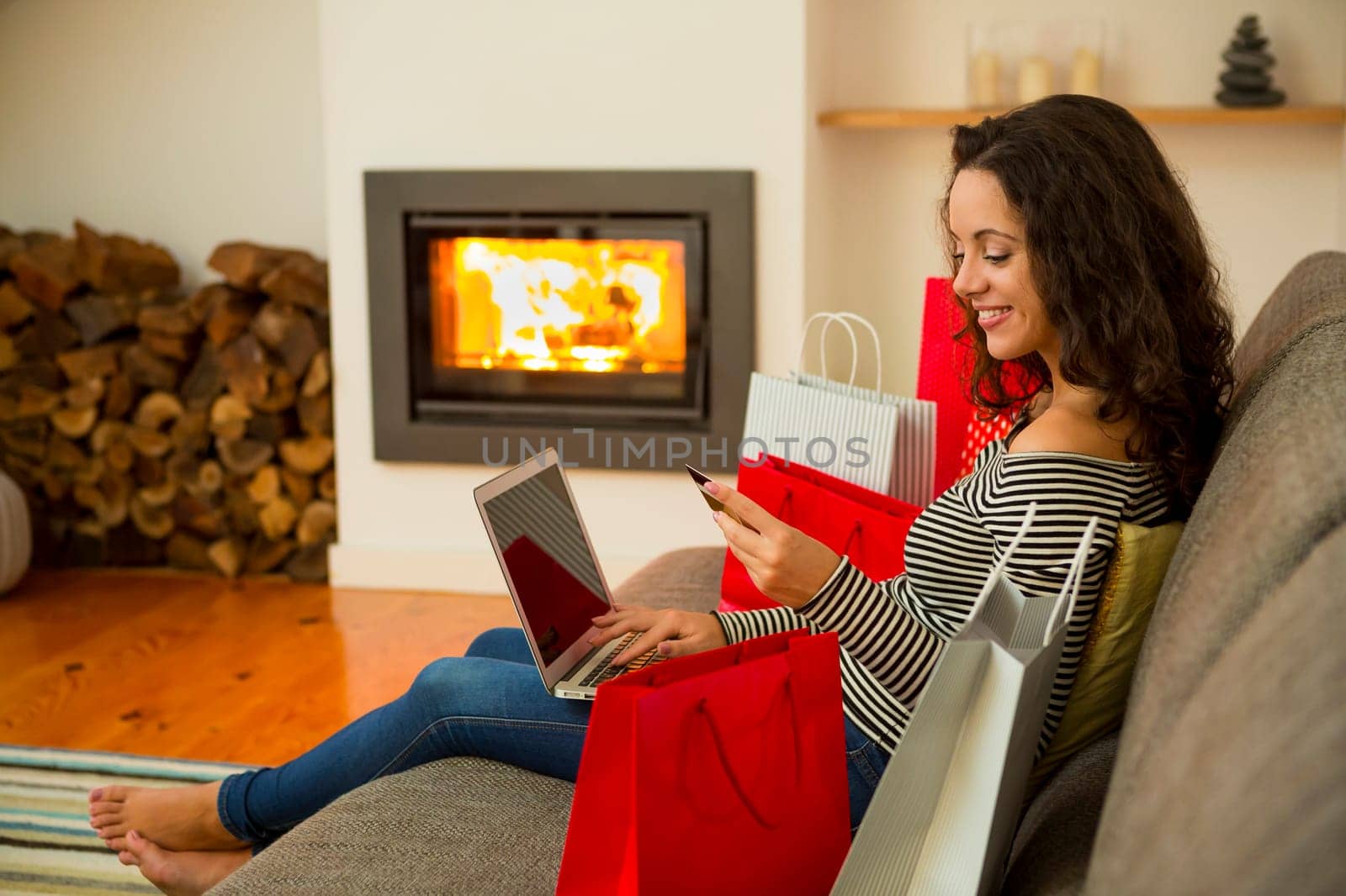 Beautiful woman at home at the warmth of the fireplace, shopping online
