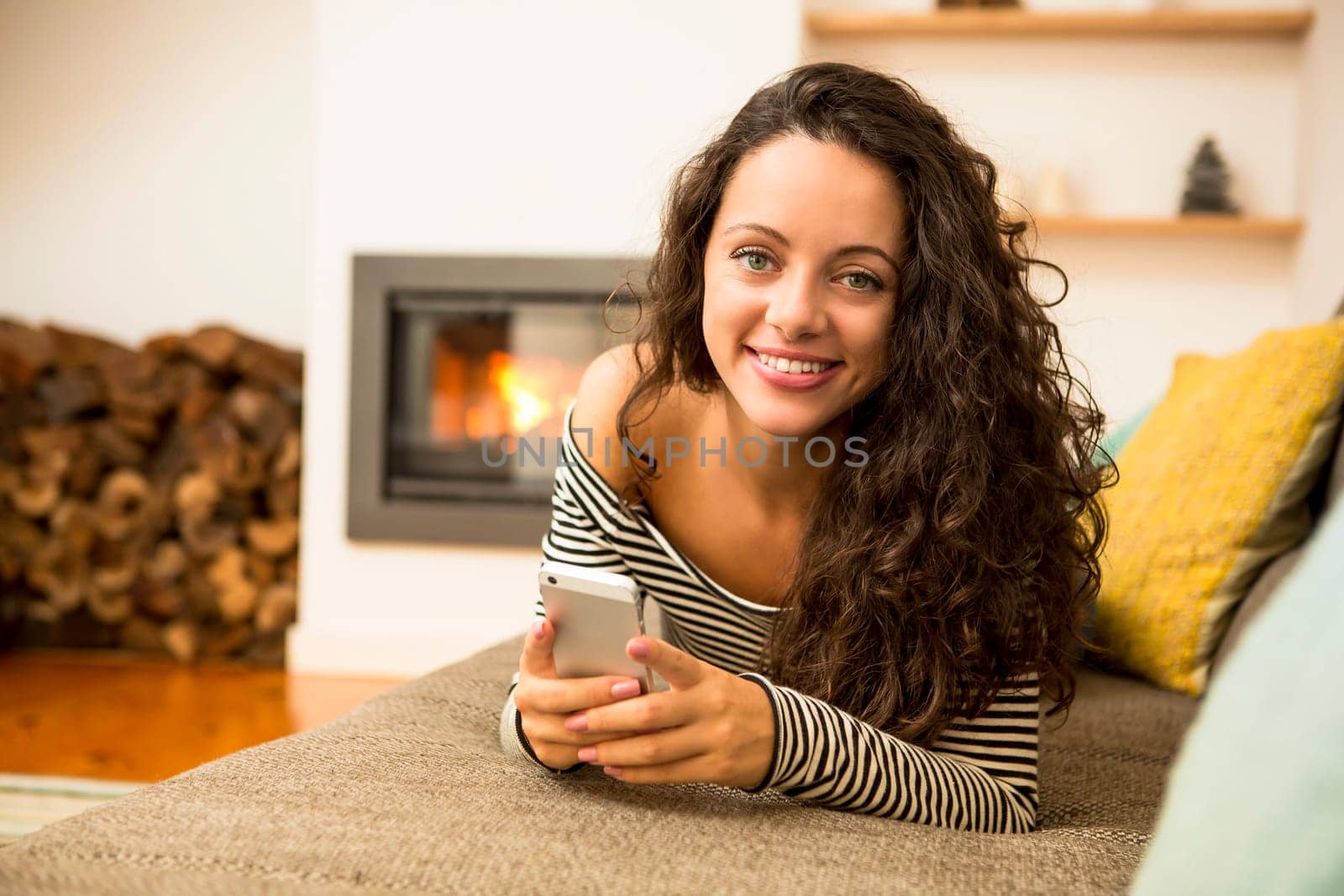 Beautiful woman listen music at home at the warmth of a fireplace