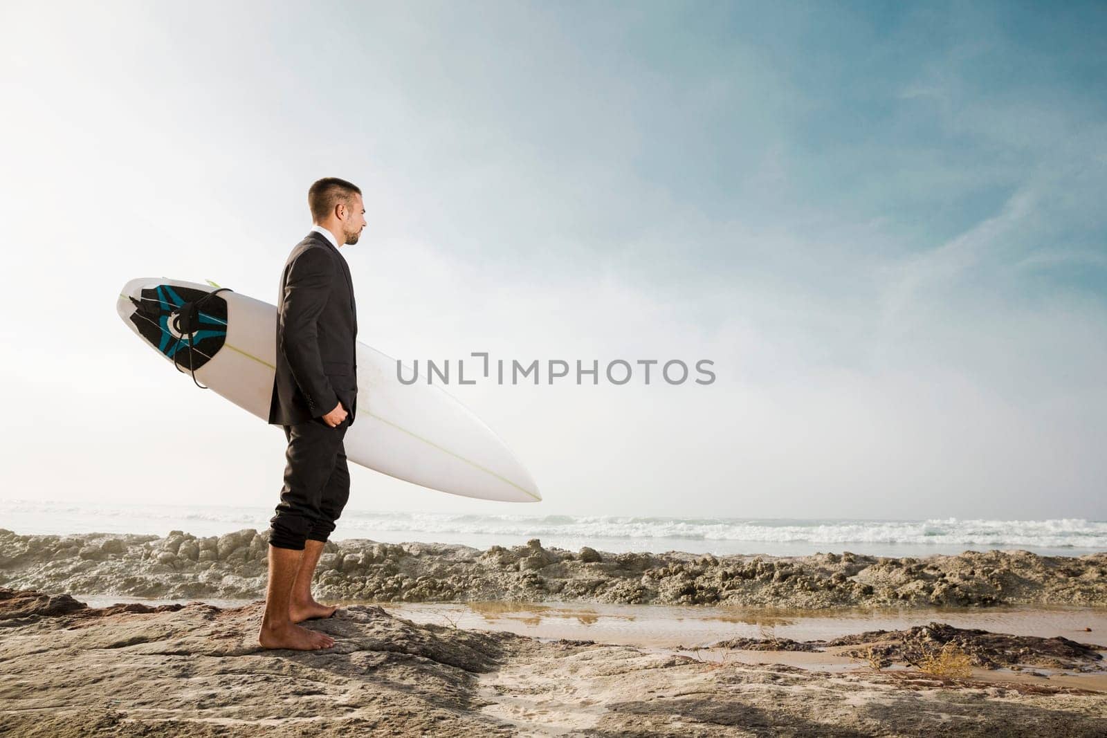 A Businessman holding is surfboard after a long day of work