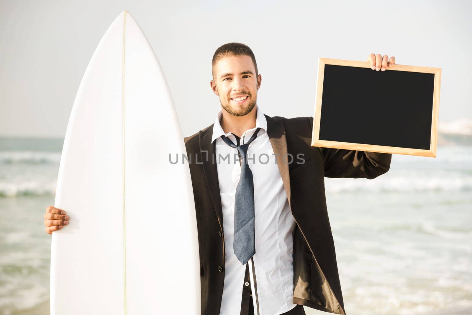 Businessman holding a chalkboard and is surfboard. Concept about a man starting a new life.
