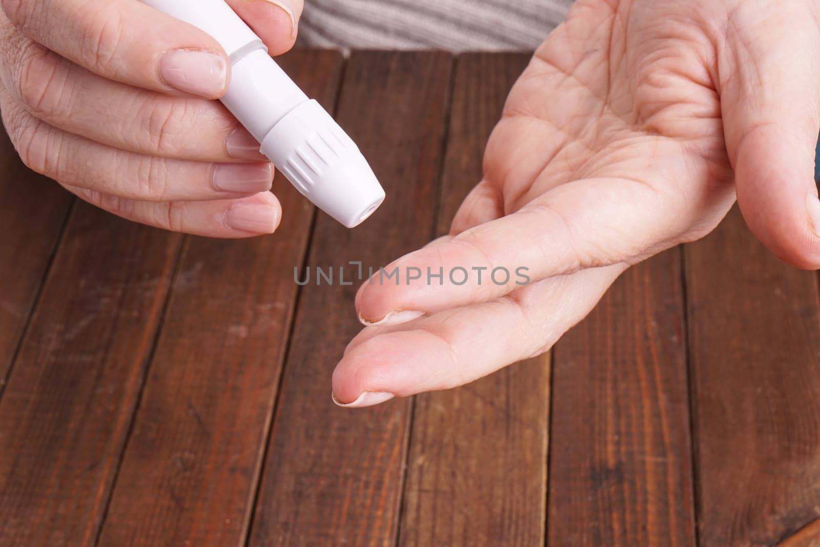 a lady&#39 s hands measuring blood glucose with a home test to control her diabetes