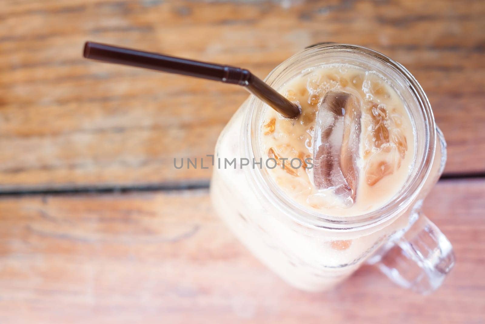 Glass of iced coffee on wooden table with vintage filter style, stock photo