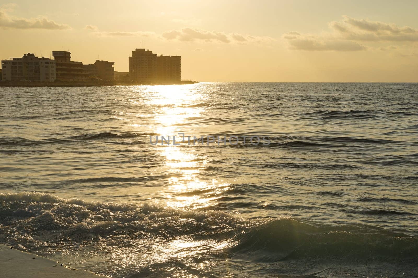 Sunset over the sea with the silhouette of the city in the background