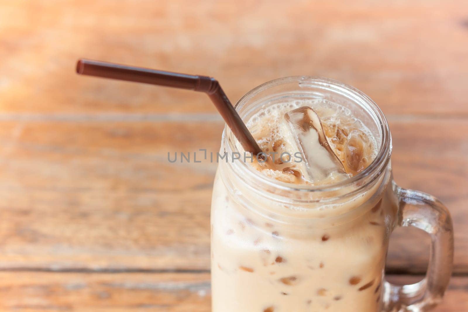 Glass of iced coffee on wooden table with vintage filter style, stock photo
