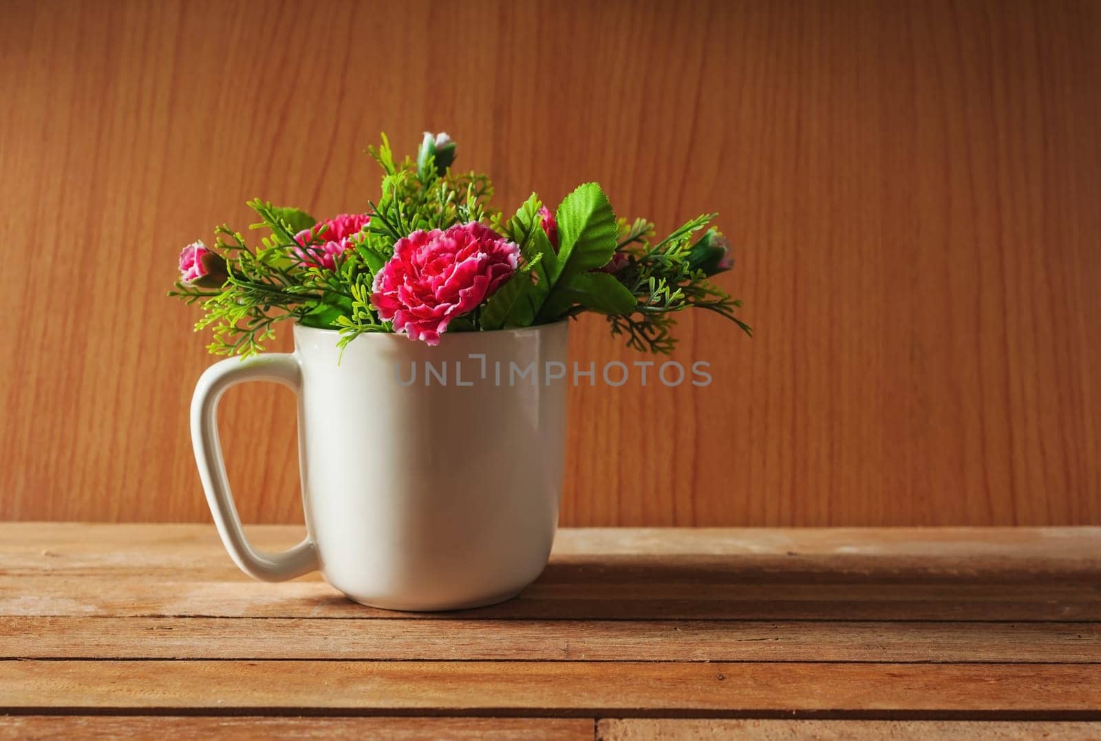 Artificial flower in cup on wooden background, Still life tone
