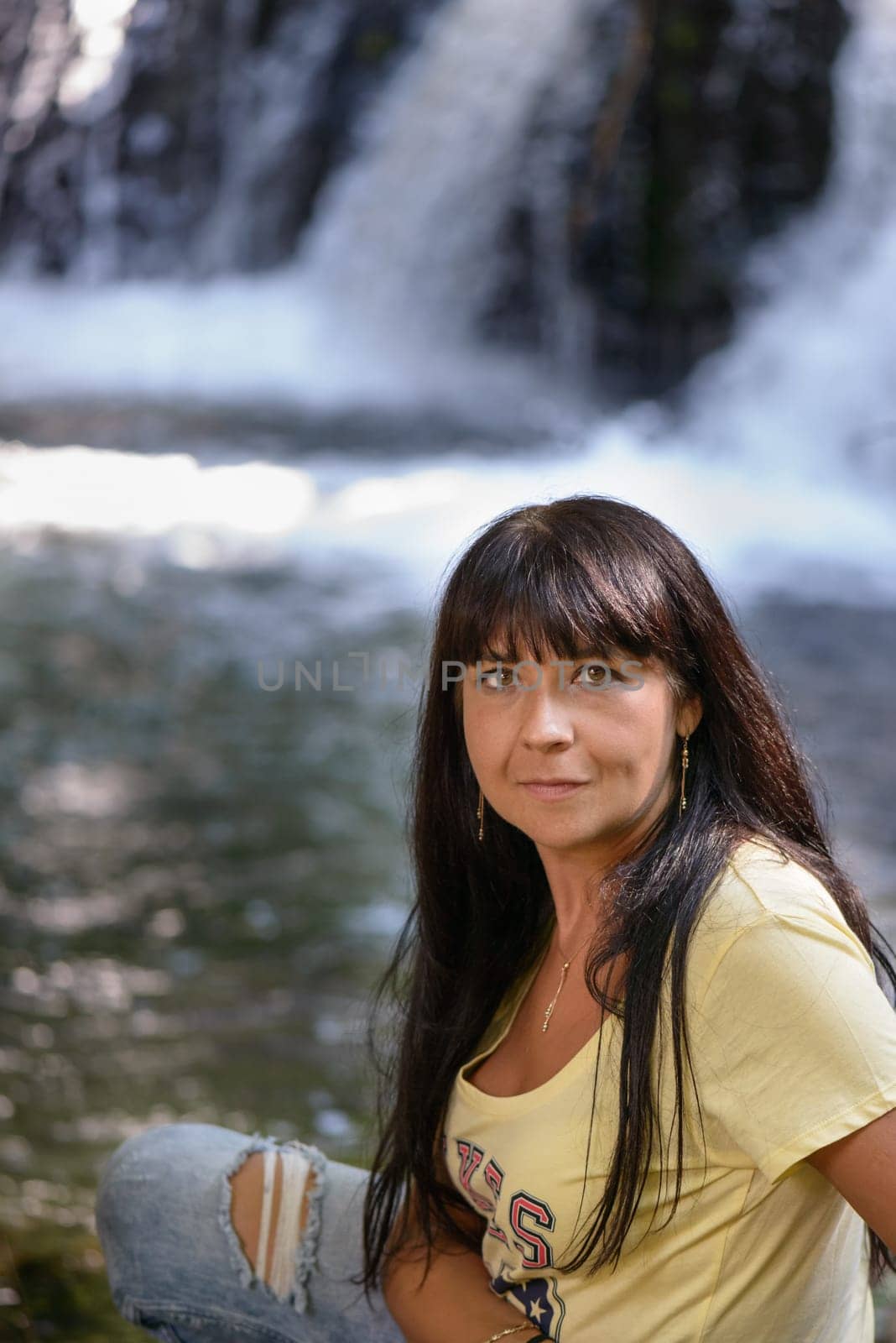 Nice girl posing on a side of a little river near waterfall in Italy