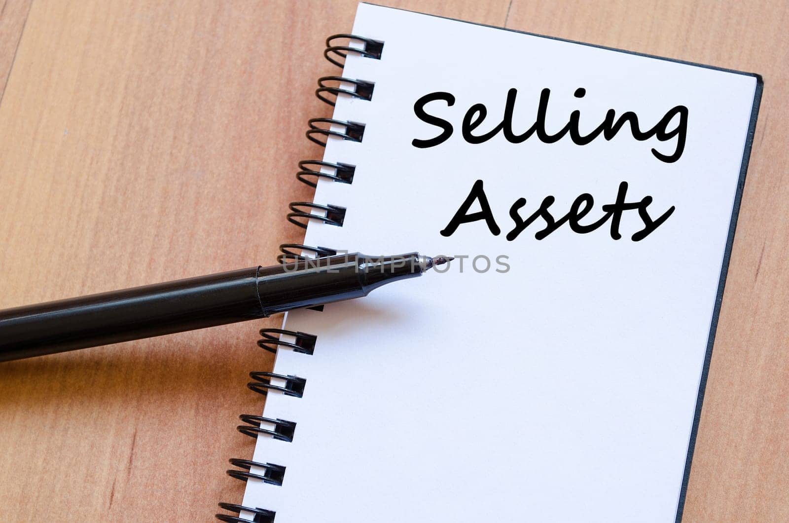 Selling assets text concept write on notebook with pen