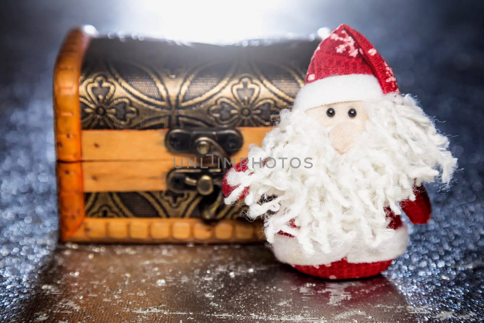 Christmas Santa Claus or Father Frost and wooden chest on silver or metal grunge surface with backlight from behind