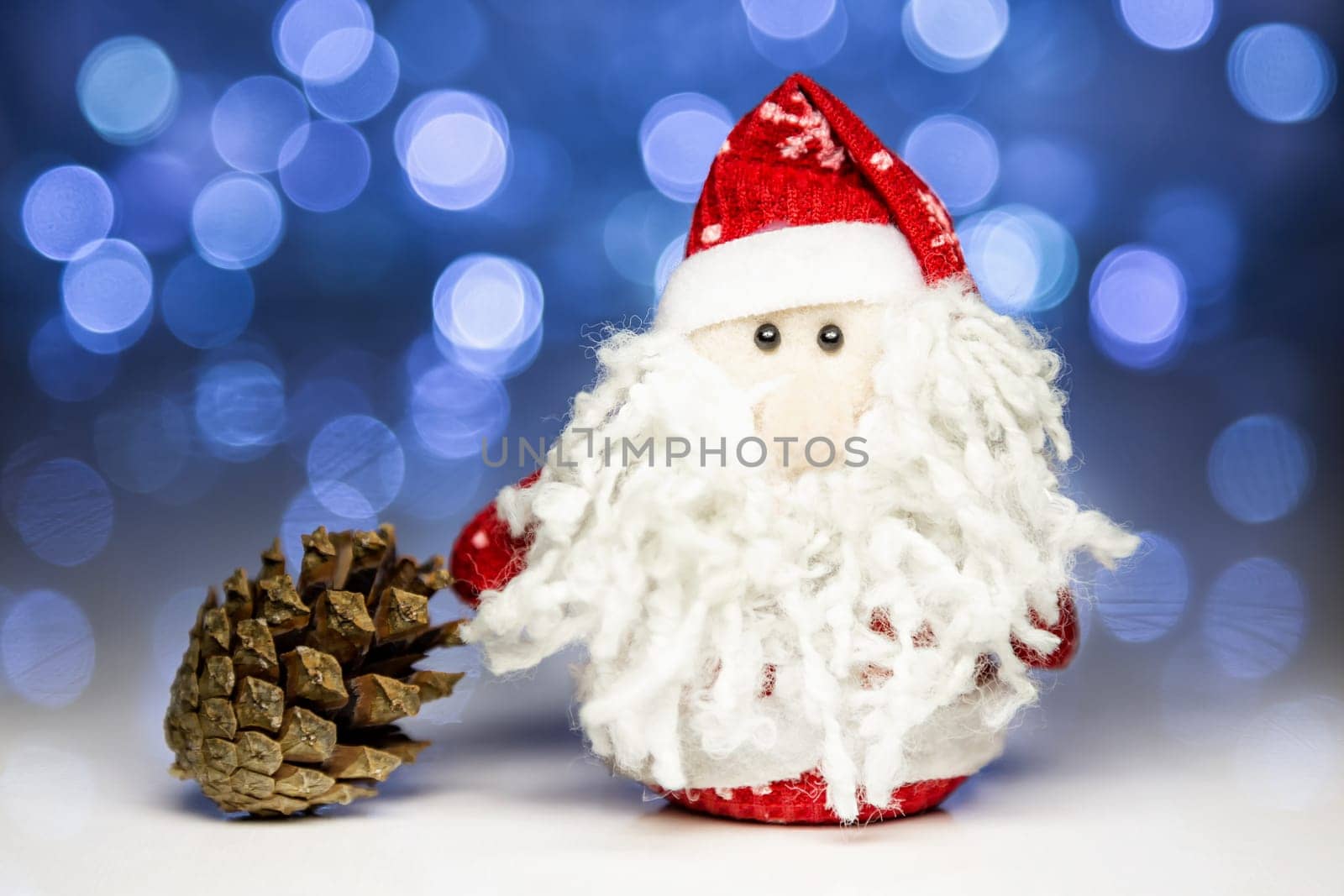 Santa Claus or Father Frost and pine cone with Christmas lights at background on white surface