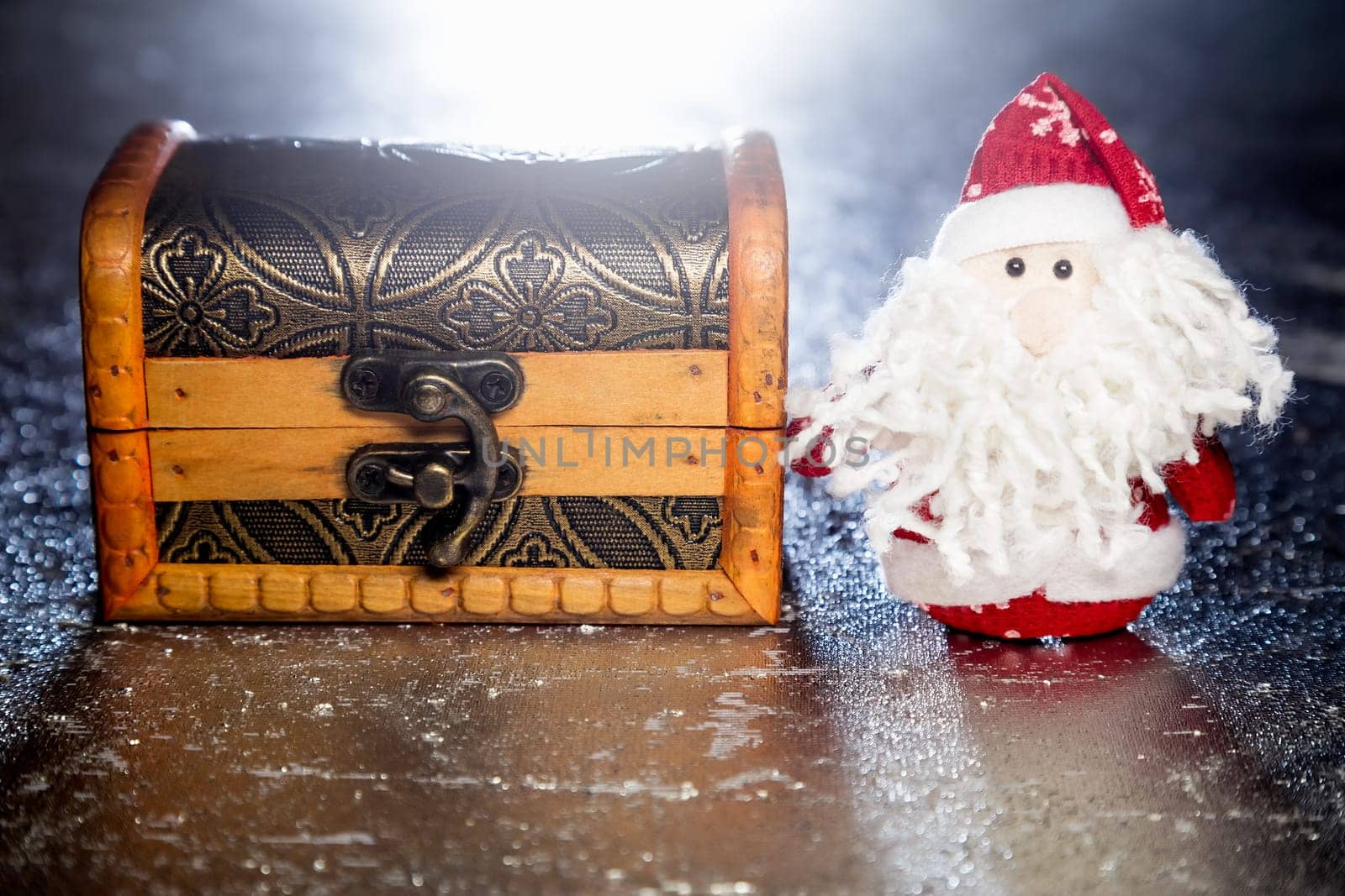 Christmas Santa Claus or Father Frost and wooden chest on silver or metal grunge surface with backlight from behind