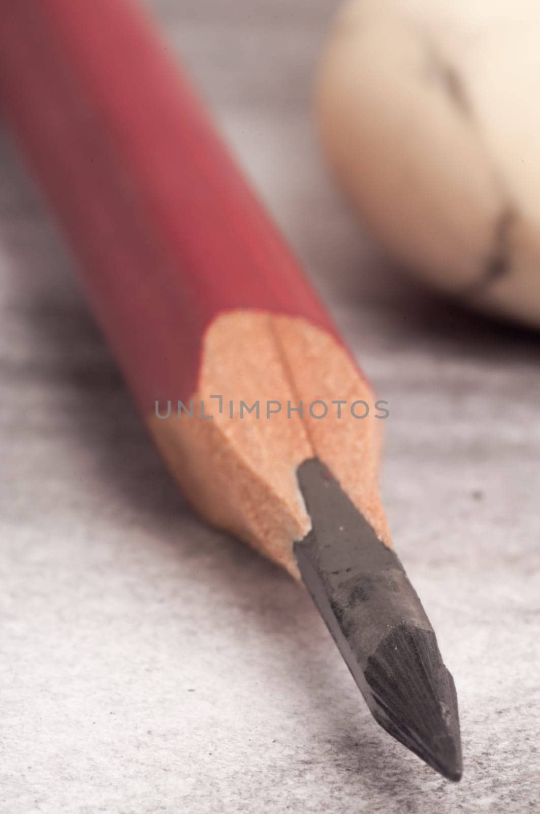 A pencil and eraser photographed up close as it is lying on an already completed pencil drawing.